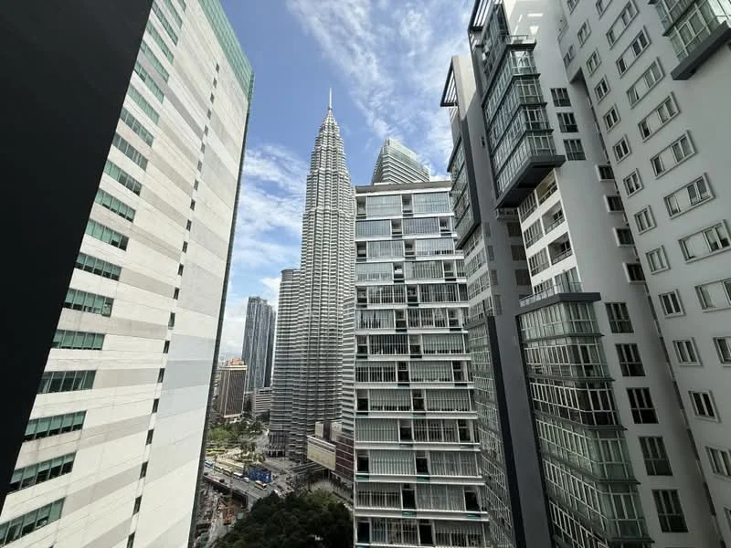 Exterior type: high-rise condominium; features: glass curtain wall, recessed balconies, approximately 50-storey high-rise, surrounded by urban skyline, view of Petronas Twin Towers, modern architectural design; style: modern.
