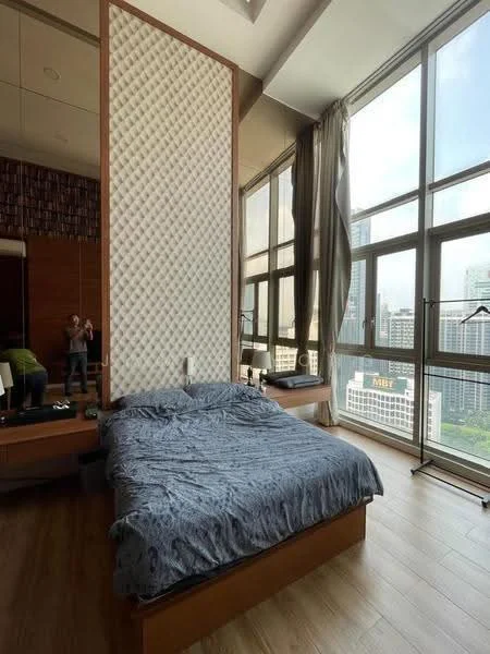 Bedroom features: king-size bed with blue bedding, wooden bed frame, large floor-to-ceiling windows, city view, wooden flooring, decorative wall panel with quilted pattern, built-in wooden wardrobe, nightstand with lamp, wall-mounted mirror, curtains for window treatment; style: modern; view: city.