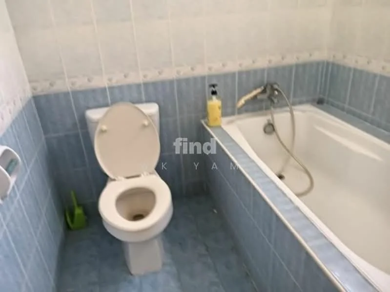 Bathroom features: white toilet, bathtub with showerhead, blue tiled walls, blue tiled flooring, toilet paper holder, soap dispenser, green storage container.