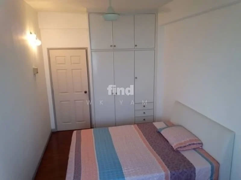 Bedroom features: queen-size bed with upholstered headboard, bedding with patterned design, built-in wardrobe with white finish, wooden flooring, white painted walls, ceiling light fixture, door with panel design, window with natural light; style: minimalist.
