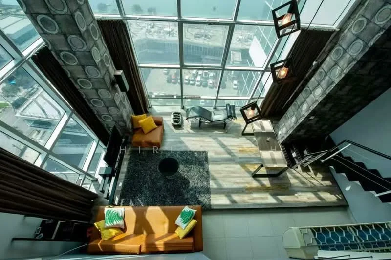 Living features: floor-to-ceiling windows, grey patterned curtains, orange 3-seater sofa, black coffee table, area rug with geometric pattern, black accent chair, wooden flooring, decorative wall lighting, staircase with metal railing, city view, open layout; style: modern; view: city.