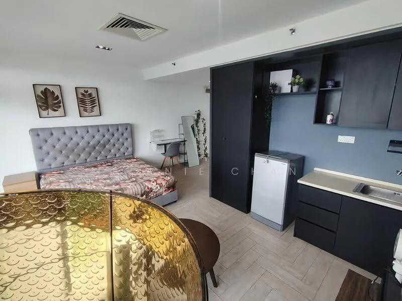 Room features: queen-size bed with upholstered headboard, bedding with floral pattern, grey accent wall, wooden flooring, built-in wardrobe, kitchenette with black cabinetry, stainless-steel sink, mini fridge, countertop with grey finish, wall-mounted shelves, decorative plants, artwork on walls, table with round top, chair; style: modern.