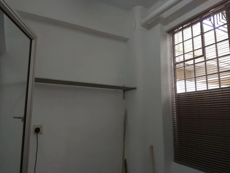 Room features: white painted walls, shelf mounted on wall, window with wooden blinds, flooring not visible.