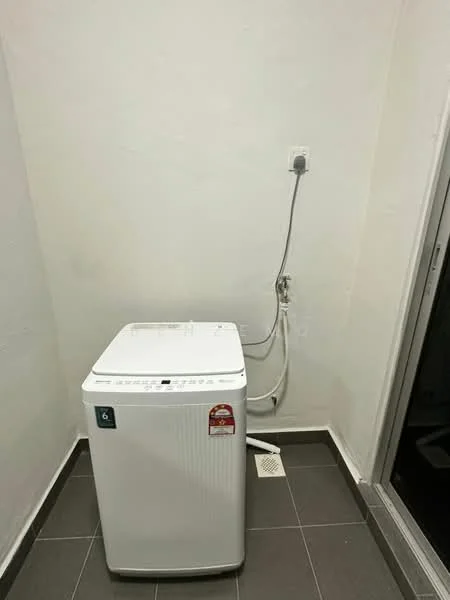 Laundry features: top-load washing machine in white, grey tiled flooring, white painted walls, drainage outlet on floor, water supply connection, plug socket on wall.