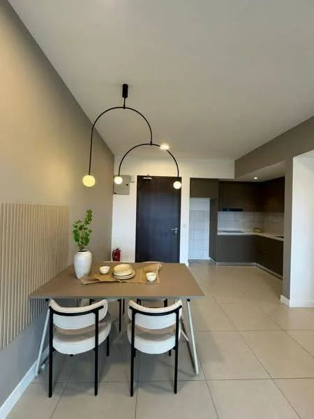 Dining features: dining table with beige surface, 3 dining chairs with black frames and beige upholstery, pendant light fixture with three bulbs, grey painted walls, tile flooring, wall-mounted air conditioning unit, kitchen area visible in background with dark cabinetry, white tiled backsplash in kitchen; style: modern.