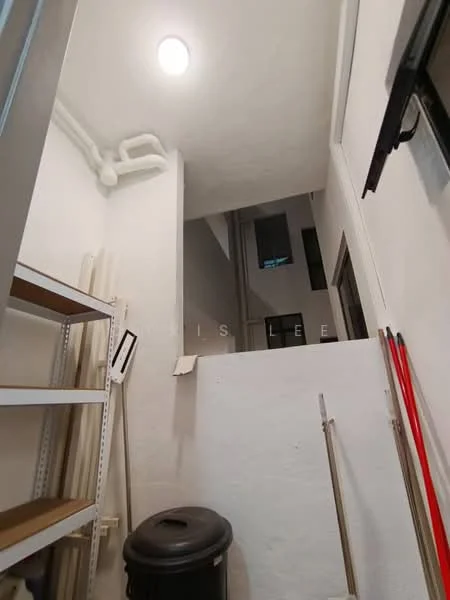 Room features: white painted walls, concrete flooring, overhead ceiling light, shelving unit, trash bin, pipes visible on wall.