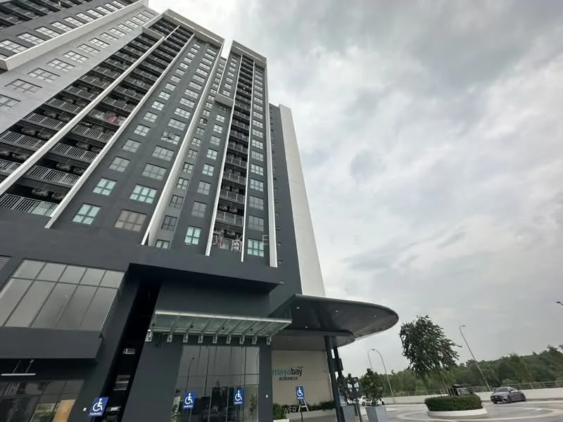Exterior type: high-rise condominium; features: glass curtain wall, grey painted facade, recessed balconies, feature lighting at night, approximately 20-storey high-rise, manicured landscaping, covered entrance with awning, visible signage, surrounded by greenery; style: modern.