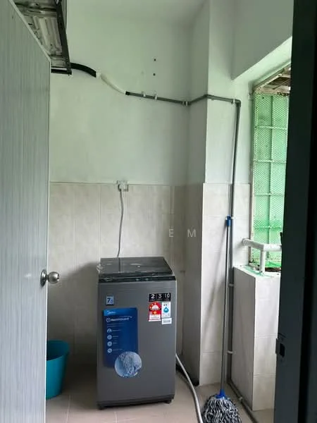 Laundry features: top-load washing machine, grey appliance, tile flooring, light grey tiled walls, green window with mesh screen, plastic laundry basket in blue, mop, water pipe, electrical outlet, wall-mounted shelf, cleaning supplies.