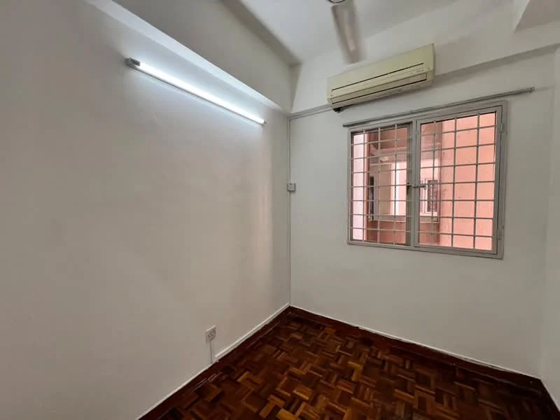 Room features: white painted walls, parquet wood flooring, 1 wall-mounted split AC, window with metal grille, ceiling light fixture, natural light from window.