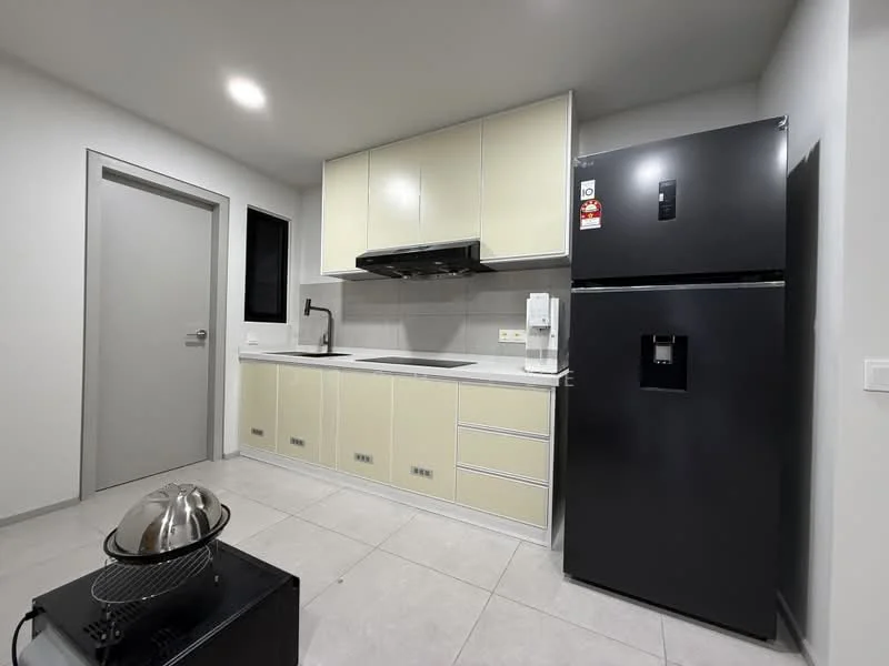 Kitchen features: light yellow cabinetry, black countertop, stainless-steel sink, chrome pull-down faucet, built-in oven, black refrigerator, ceramic tile flooring, grey wall tiles, exhaust hood, wall-mounted microwave, single-bowl sink, kitchen island, under-cabinet lighting; style: modern.