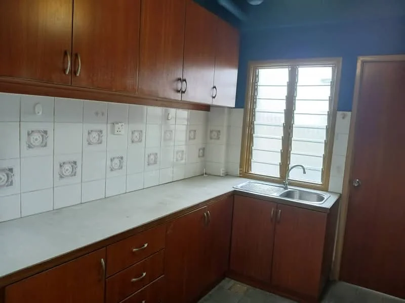 Kitchen features: wooden cabinetry, grey countertop, stainless-steel sink, chrome faucet, white tiled backsplash with floral pattern, window with metal grille, laminate flooring, wall-mounted cabinets, door leading to outside.