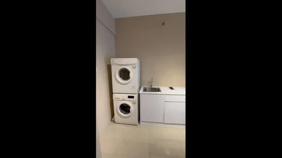 Laundry features: front-load washing machine, tumble dryer stacked, single-bowl stainless-steel sink, white cabinetry, light-colored walls, glossy tile flooring, countertop space, plumbing fixtures; style: modern.