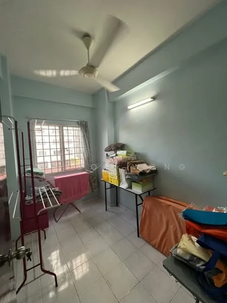 Room features: light blue painted walls, white tiled flooring, ceiling fan, window with sheer curtains, metal clothing rack, black metal table, stacked boxes, folded blankets, laundry drying rack.