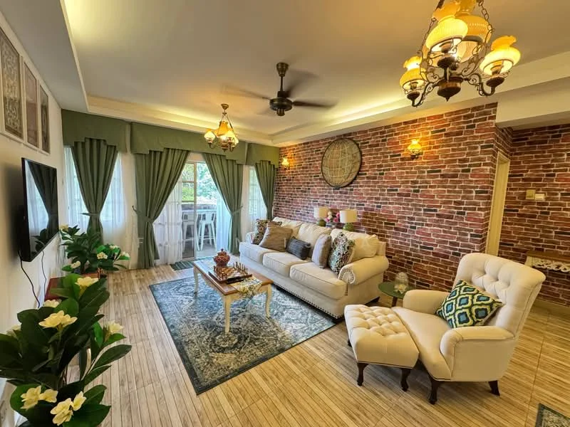 Living features: 3-seater fabric sofa in cream, armchair in white fabric, coffee table with wooden legs, area rug with intricate pattern, brick accent wall, green curtains, ceiling fan with light, chandelier with multiple bulbs, wall-mounted TV, decorative wall clock, houseplants in ceramic pots, decorative cushions with various patterns; style: modern; view: garden.