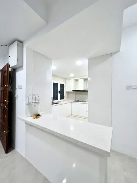 Kitchen features: white painted walls, light-colored countertop, kitchen island with breakfast bar, built-in cabinetry, stainless-steel appliances, recessed downlights, window with black frames, open layout, tile flooring; style: modern.