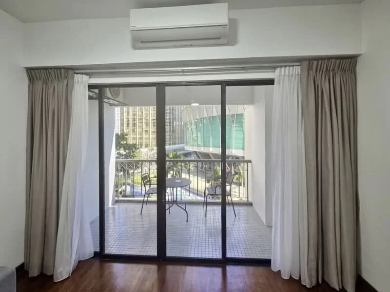 Room features: floor-to-ceiling sliding glass door, curtains in beige and white, wall-mounted split AC, wooden flooring, balcony view, outdoor table and chairs, tile flooring on balcony, greenery visible outside; style: modern; view: garden.