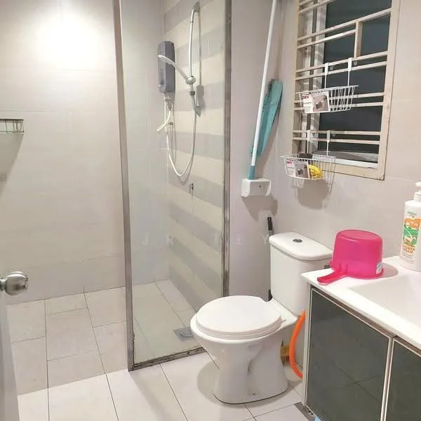 Bathroom features: glass shower enclosure, wall-mounted shower head, toilet, pink plastic basin, white vanity cabinet, grey wall tiles, white floor tiles, window with metal grille, toilet paper holder, shower caddy, cleaning supplies, soap dispenser; style: modern.