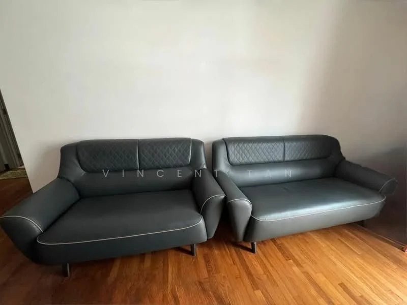 Living features: 2-seater leather sofa in dark grey, diamond quilted pattern on sofa back, wooden legs, light-colored wall, hardwood flooring; style: modern.