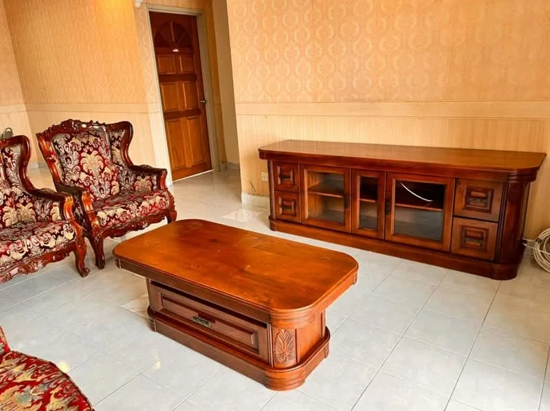 Living features: wooden flooring, cream painted walls, decorative wall paneling, two ornate armchairs with floral upholstery, wooden coffee table with drawer, wooden TV console with glass doors, door leading to hallway; style: traditional.