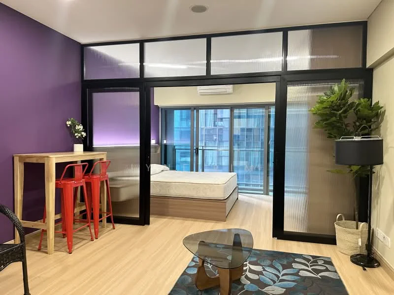 Living features: purple accent wall, light wood flooring, glass sliding doors, floor-to-ceiling windows, black framed partition, bar table with red stools, decorative plant, area rug with floral pattern, coffee table, wall-mounted air conditioning unit; style: modern; view: city. Bedroom features: queen-size bed, bedding visible, natural light from windows; style: modern; view: city.