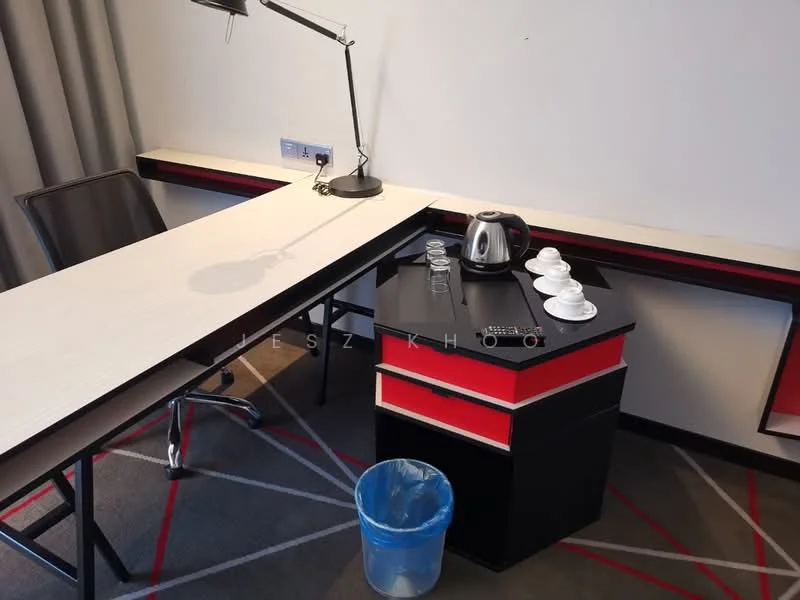 Study features: black and red cabinetry, white desk surface, metal desk lamp, electric kettle, glass cups on tray, black chair, carpet with geometric pattern, waste bin; style: modern.