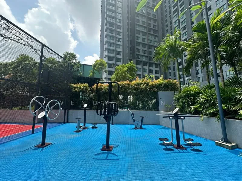 Exterior type: clubhouse; features: outdoor gym equipment, rubberized flooring, surrounded by greenery, basketball court in background, tall residential buildings in background, sunny weather, palm trees, fencing around gym area; style: modern.