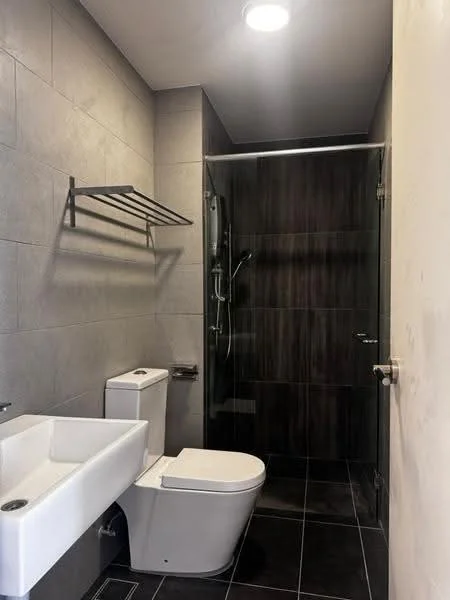 Bathroom features: grey tiled walls, black tiled flooring, walk-in shower with glass enclosure, rain shower head, handheld shower, white wall-mounted sink, one-piece toilet, towel rack, recessed ceiling light; style: modern.