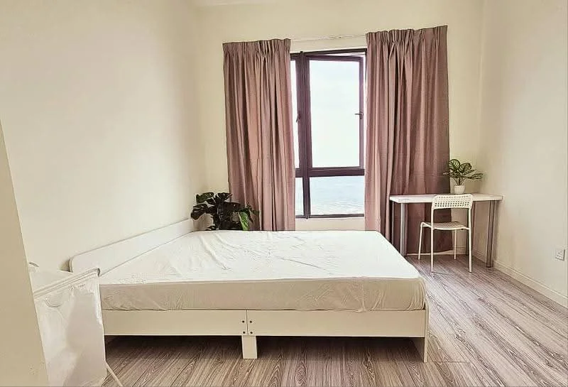 Bedroom features: queen-size bed frame without mattress, light wood flooring, white painted walls, floor-to-ceiling window, curtains in light brown, small desk with white chair, indoor plant in ceramic pot, natural light from window; style: modern; view: sea.