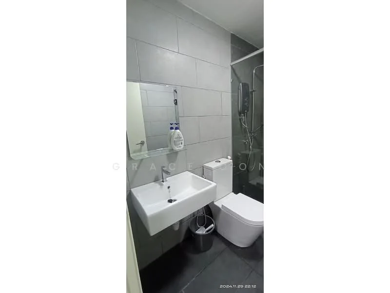 Bathroom features: grey tiled walls, black tiled flooring, single-sink vanity with white cabinet, chrome basin mixer faucet, framed mirror, one-piece toilet, walk-in shower with glass enclosure, handheld shower, shower wall with tile cladding, waste bin; style: modern.