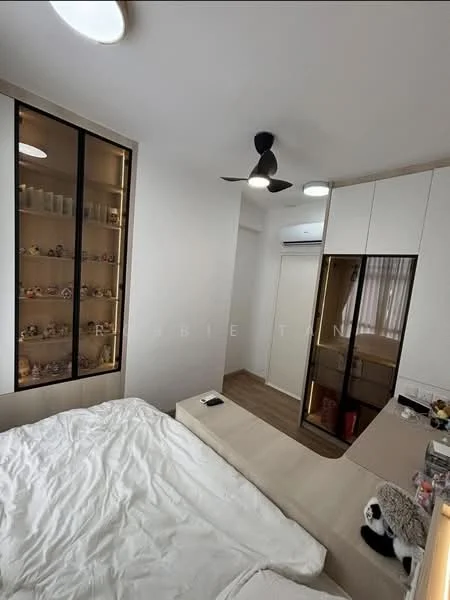 Bedroom features: queen-size bed with white bedding, wooden flooring, 5-blade ceiling fan with light, built-in wardrobe with sliding doors, wall-mounted air conditioning unit, decorative shelving unit with glass doors, study desk, wall-mounted light fixtures, window with sheer curtains; style: modern.