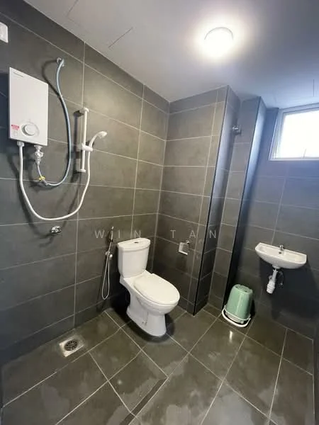 Bathroom features: grey ceramic tile flooring, grey tiled walls, one-piece toilet, chrome basin mixer faucet, wall-mounted shower with handheld showerhead, shower wall with glass partition, small wall-mounted sink, water heater unit, window for natural light, exhaust fan, towel rack; style: modern.
