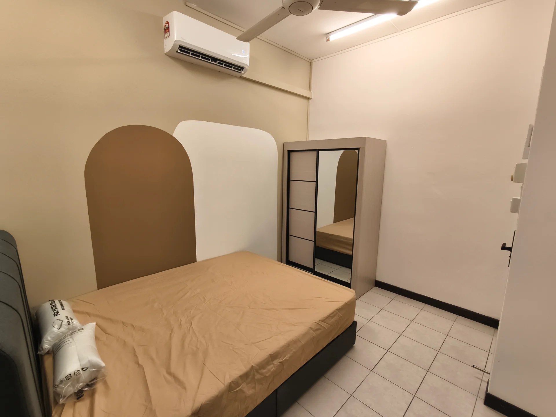 Bedroom features: queen-size bed with beige bedding, wall-mounted split AC, mirror-front wardrobe, light-colored accent wall, white walls, ceramic tile flooring, ceiling fan, window with blinds; style: modern.