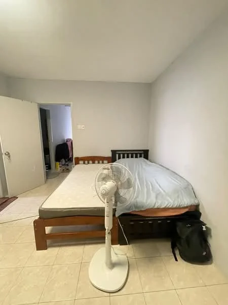 Bedroom features: queen-size bed with mattress, white bedding, wooden bed frame, standing fan, light-colored tiled flooring, grey painted walls, open door leading to another room, backpack on the floor.