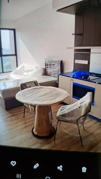 Living features: wooden flooring, large window with city view, sofa with protective covering, round dining table, two dining chairs, kitchen cabinetry with blue accents, built-in kitchen countertop, open layout, light-colored walls, recessed lighting; style: modern; view: city.