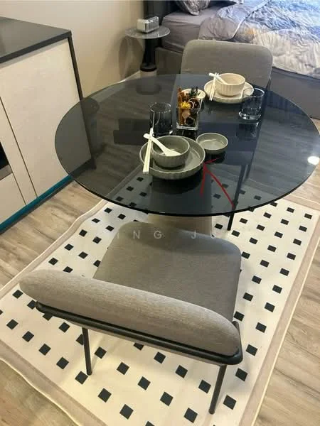 Dining features: round glass dining table, 4 grey upholstered dining chairs, decorative table setting with bowls and utensils, black and white geometric area rug, side table with decorative items, bed visible in background, neutral wall color, modern design; style: modern.