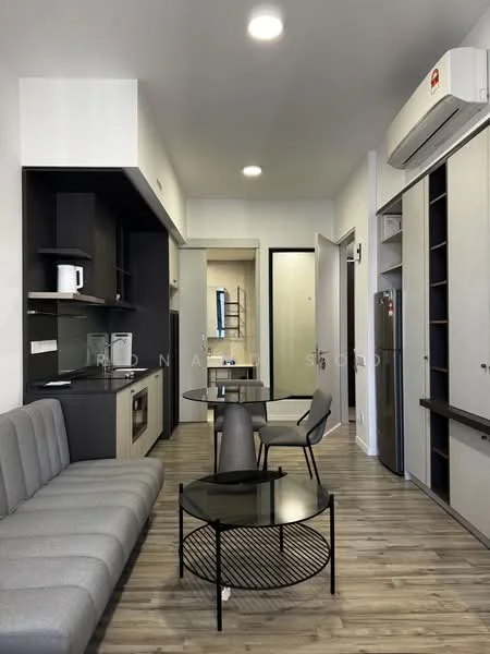 Living features: grey fabric sofa, round black coffee table, wall-mounted air conditioning unit, open kitchen layout, kitchen cabinets in black and beige, built-in oven, stainless-steel fridge, wooden flooring, recessed ceiling lights, dining table with two chairs, wall-mounted shelves, doorway leading to bathroom, doorway leading to hallway; style: modern.