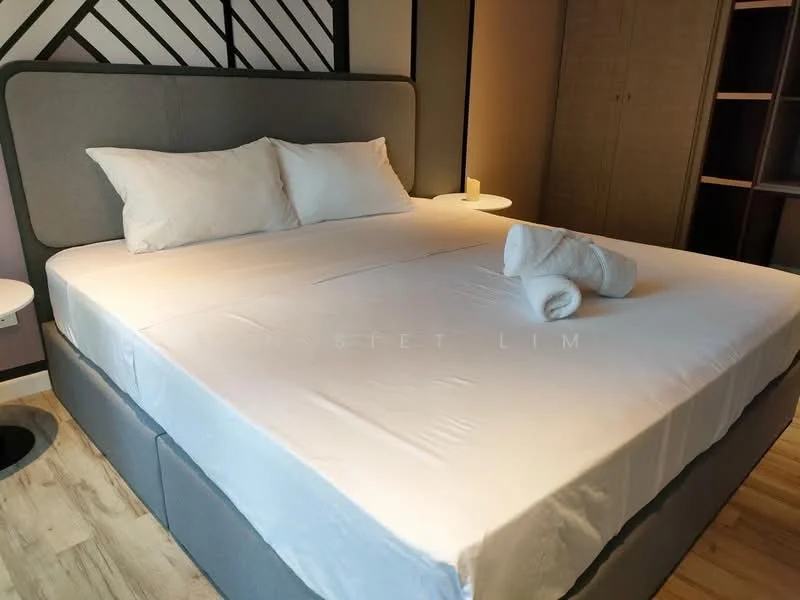 Bedroom features: king-size bed, upholstered headboard, white bedding, two white pillows, rolled white towel, nightstand with lamp, wooden flooring, built-in wardrobe, decorative wall paneling; style: modern.