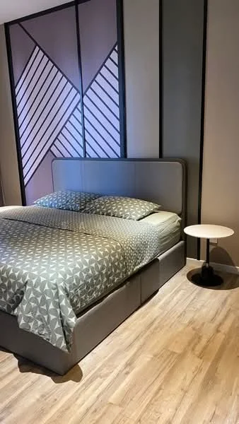 Bedroom features: king-size bed with upholstered headboard, geometric patterned bedding, light wood flooring, decorative accent wall with geometric design, side table with black base, soft lighting, neutral wall color; style: modern.