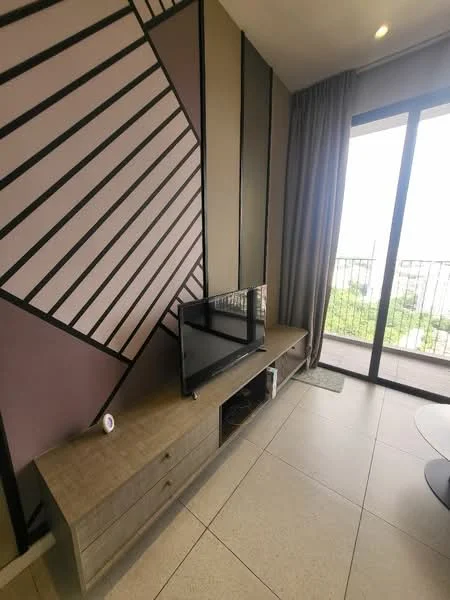 Living features: flat-screen TV on console, wooden TV console with drawers, geometric accent wall with pink and grey tones, floor-to-ceiling sliding glass door, curtains, tile flooring, area rug, outdoor view from balcony; style: modern; view: garden.