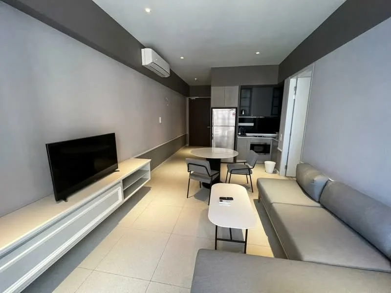 Living features: grey fabric sofa, coffee table, TV console, wall-mounted TV, recessed downlights, air conditioning unit, white walls, light grey accent wall, tile flooring, open layout, dining table, kitchen area visible; style: modern.