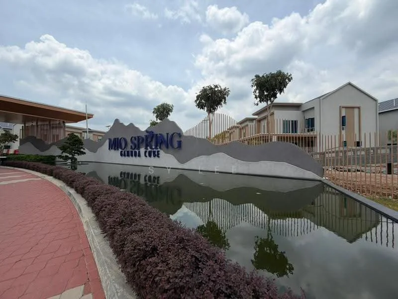 Exterior features: water feature with reflection, landscaped garden with shrubs, signage with 'Mio Spring', modern architectural design, paved walkway, trees in the background, fencing around the property, cloudy sky; style: modern.