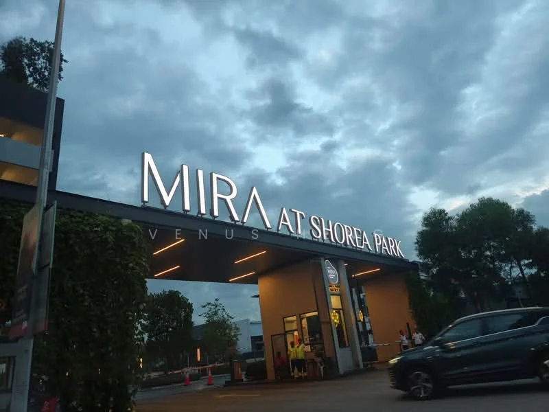 Exterior features: illuminated building sign, modern entrance, landscaped greenery, paved driveway, cloudy sky, visible vehicles, outdoor lighting; style: modern.