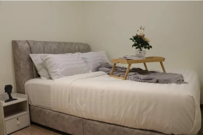 Bedroom features: king-size bed with upholstered headboard, white bedding, grey throw blanket, wooden bed frame, nightstand with drawer, decorative plant on tray, table with magazines, laminate flooring, cream painted walls, soft lighting; style: modern.