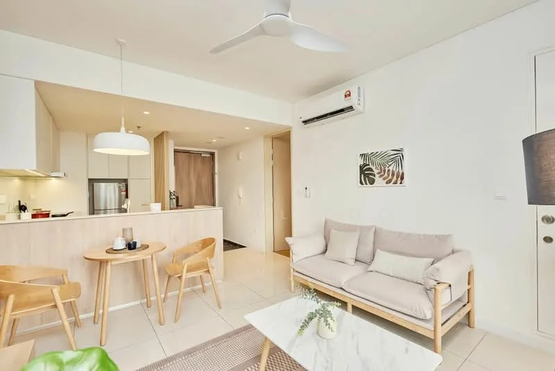 Living features: 3-seater fabric sofa in light grey, 2 wooden dining chairs, coffee table with marble top, wall-mounted TV, recessed downlights, 5-blade ceiling fan, wall-mounted split AC, light-colored tiled flooring, white painted walls, decorative wall art, area rug with geometric pattern; style: modern. Kitchen features: white cabinetry, stainless-steel fridge, built-in oven, ceramic cooktop, kitchen island with seating, light-colored countertops; style: modern.