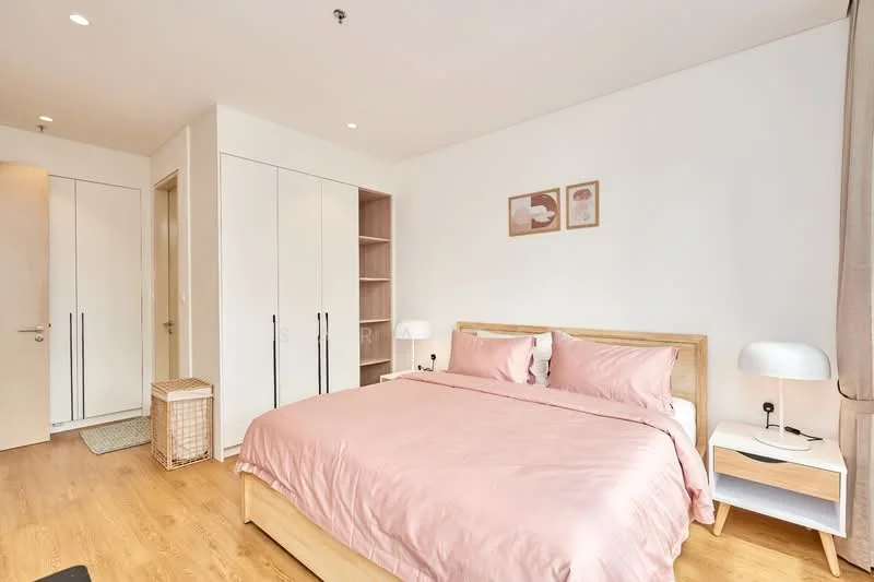 Bedroom features: king-size bed with pink bedding, wooden bed frame, two bedside lamps, white painted walls, wooden flooring, built-in wardrobe with sliding doors, framed artwork on walls, decorative storage basket, curtains, open shelving unit; style: modern.