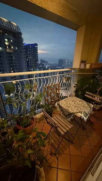 Balcony features: terracotta tile flooring, metal railing, small round table, two folding chairs, potted plants, city skyline view, decorative wall art; style: modern; view: city.