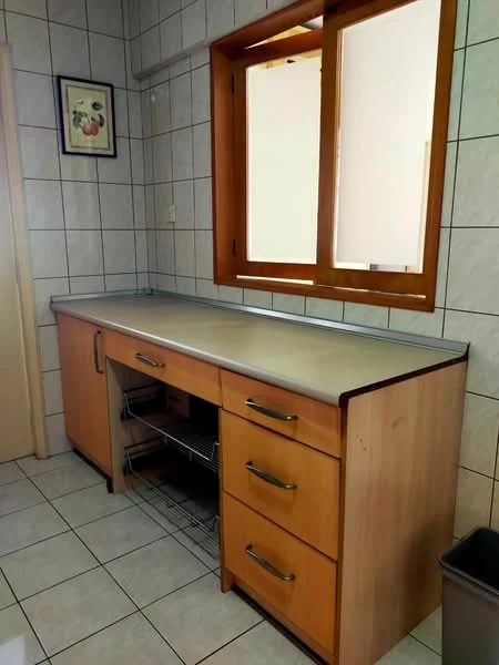 Kitchen features: laminate countertop, wood cabinetry with drawers, stainless-steel handles, open shelving, tiled walls, ceramic tile flooring, window with wooden frame, under-counter storage.