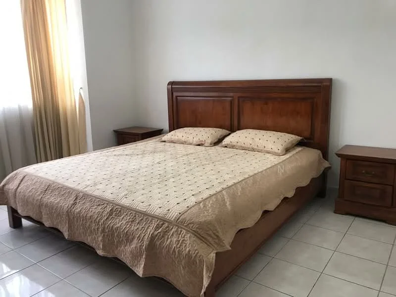 Bedroom features: king-size bed, wooden headboard, beige quilted bedspread, two bedside tables, lamps on bedside tables, white painted walls, tiled flooring, curtains in light yellow, window with natural light; style: traditional.