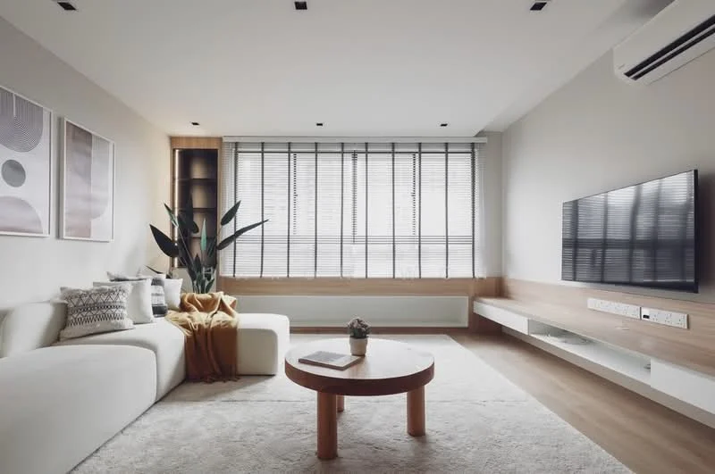Living features: L-shape sectional sofa in white, coffee table with round top, wall-mounted TV, TV console with built-in storage, light wood paneling, recessed ceiling lights, floor-to-ceiling windows with blinds, decorative houseplants, area rug with neutral color, throw blanket on sofa; style: modern.