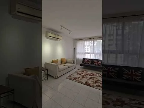 Living features: 3-seater fabric sofa in white, 2-seater fabric sofa with Union Jack pattern, area rug with geometric pattern, floor-to-ceiling windows, sheer curtains, wall-mounted split AC, recessed downlights, light-colored walls, tile flooring, coffee table, decorative cushions; style: modern; view: city.
